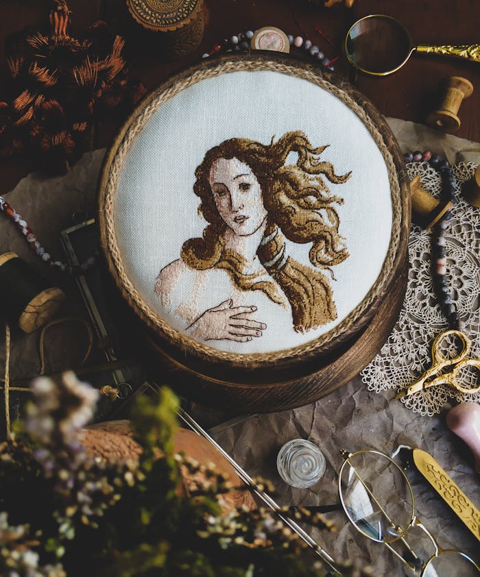 Home A detailed embroidery of a classical artwork captured in a creative, vintage setting.