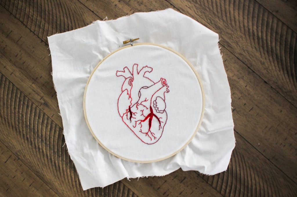 Home Close-up of embroidered anatomical heart on canvas, symbolizing creativity and craft.